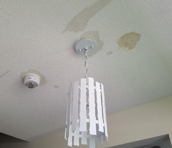 ceiling light with water marks beside it on white popcorn ceiling