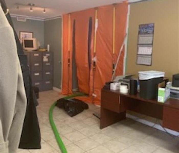An Office With Desks, A Green Hose Leading Behind Orange Poly Containment