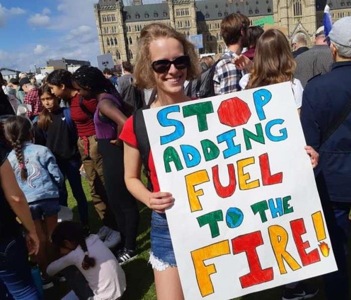 A Young Woman Holding a Sign In a Crowd on Parliament Hill